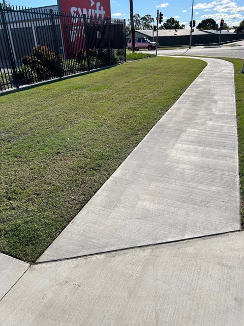A wide cut verge either side of a concrete footpath