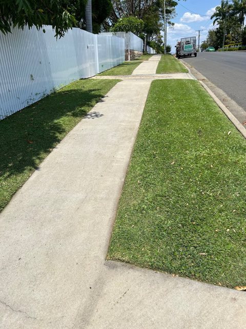 A footpath and cut verge running along a fence line toward the street