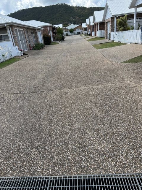 A driveway running between unit blocks with mown lawn either side