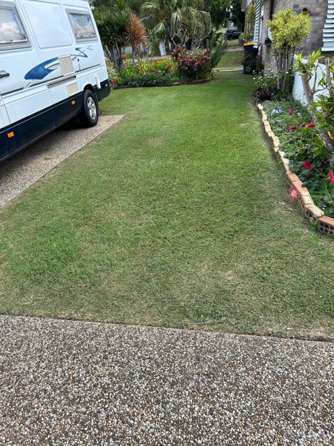 A caravan parked on a driveway beside a freshly cut lawn